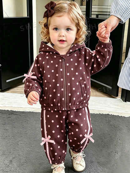 Girls Hooded Two Pieces Tracksuit In Brown With Pink Polka Dots. Full-Zip Hooded Jacket And Cuffed Jogger Pants Decorated With Pink Ribbons And Bows.