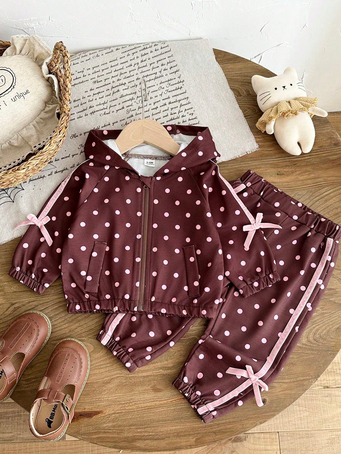 Girls Hooded Two Pieces Tracksuit In Brown With Pink Polka Dots. Full-Zip Hooded Jacket And Cuffed Jogger Pants Decorated With Pink Ribbons And Bows.
