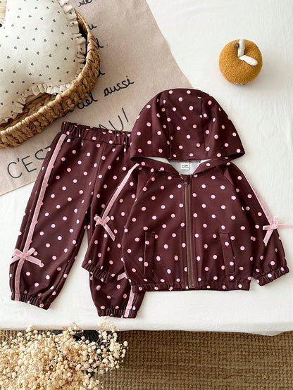 Girls Hooded Two Pieces Tracksuit In Brown With Pink Polka Dots. Full-Zip Hooded Jacket And Cuffed Jogger Pants Decorated With Pink Ribbons And Bows.