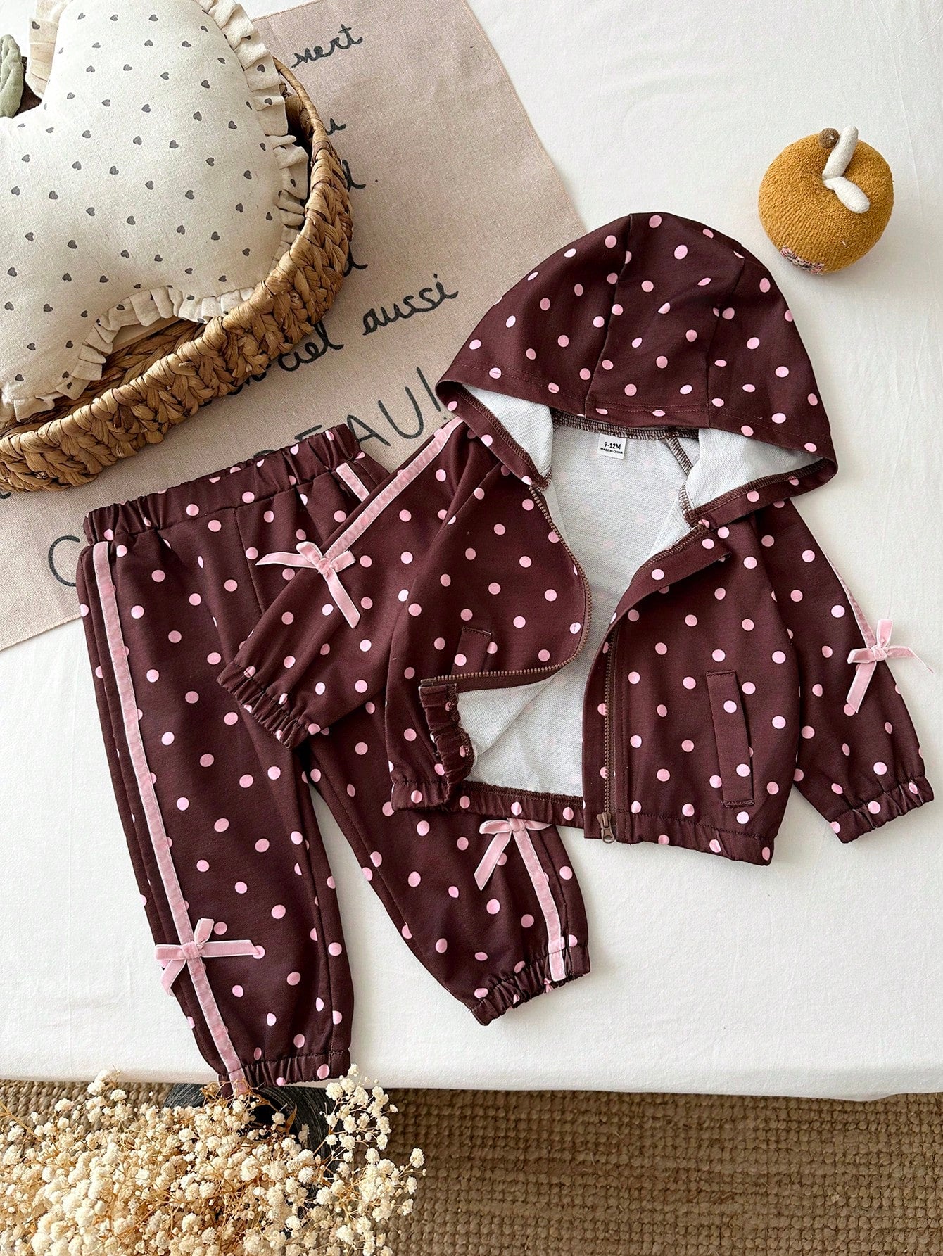 Girls Hooded Two Pieces Tracksuit In Brown With Pink Polka Dots. Full-Zip Hooded Jacket And Cuffed Jogger Pants Decorated With Pink Ribbons And Bows.